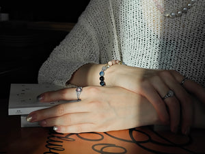 Lifestyle shot of woman with natural kyanite bracelet, amethyst ring and pearl necklace
