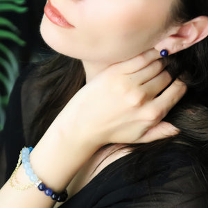 woman wearing earth earrings feature lapis lazuli and sterling silver studs, symbolizing wisdom, grounding, and honest expression.