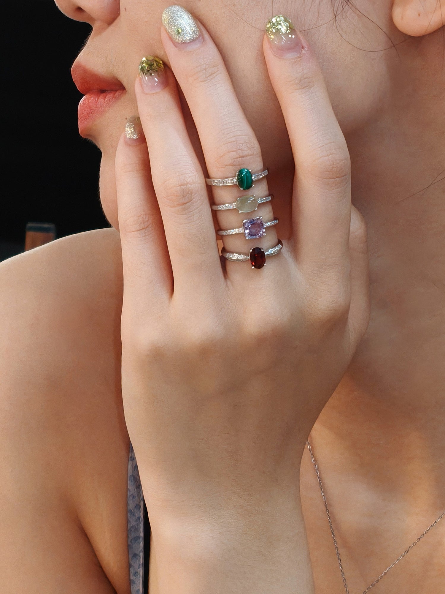 Close-up of girl wearing multiple silver rings with gemstones: prehnite, garnet, lavender amethyst, and Malachite