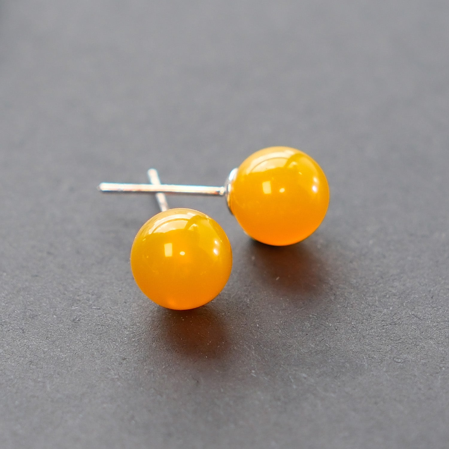 Close-up of The Sun earrings feature yellow agate and sterling silver studs, symbolizing vitality, warmth, and inner strength.