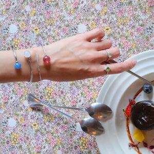 Hand wearing Peridot Ring, Prehnite Ring, double star collection bracelet with moon stone and kyanite, and comet sterling silver bracelet with strawberry quartz