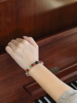 girl wearing colorful crystal bracelet playing piano