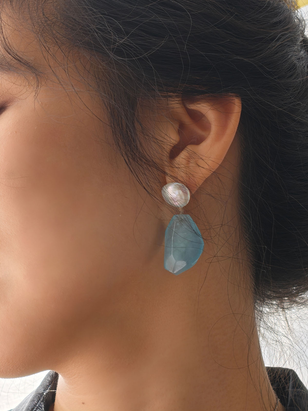 Close-up of aquamarine pearl earrings worn at a café, natural light lifestyle photo